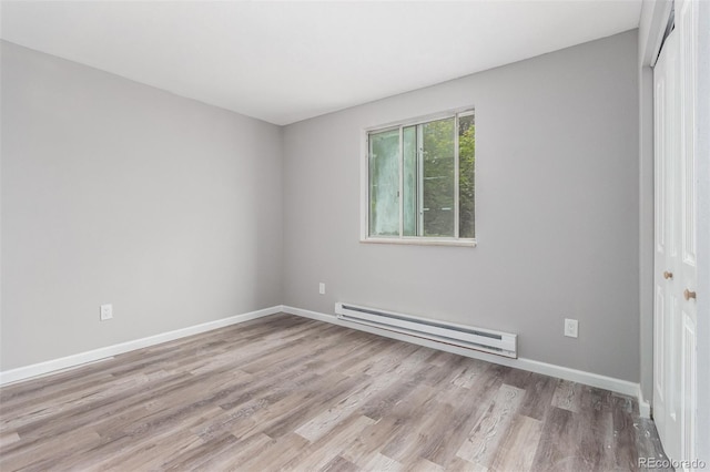 spare room with a baseboard radiator and light wood-type flooring