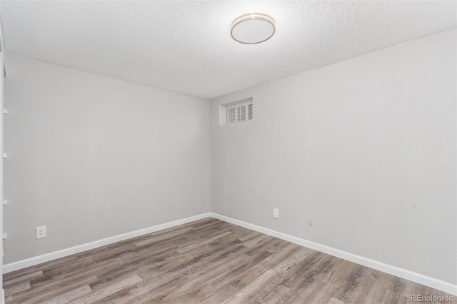 unfurnished room with a textured ceiling and wood-type flooring