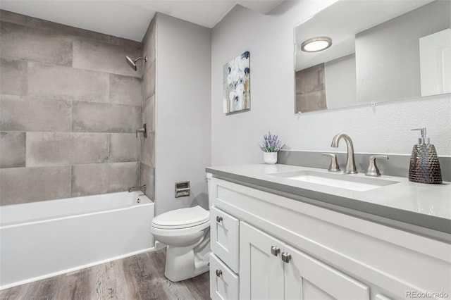 full bathroom featuring vanity, tiled shower / bath combo, wood-type flooring, and toilet