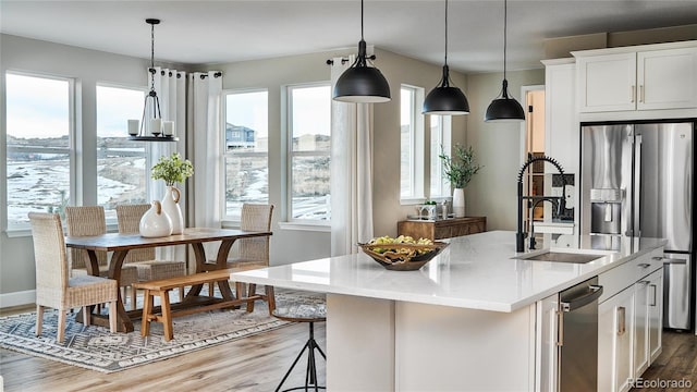 kitchen with white cabinets, a healthy amount of sunlight, and an island with sink