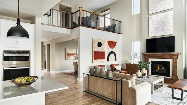 living room with light hardwood / wood-style flooring and a towering ceiling