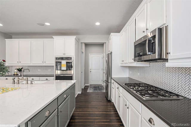 1473 Castle Creek Cir, Castle Rock, CO 80104 - kitchen featuring appliances with stainless steel finishes, white cabinetry, dark wood-style floors, and recessed lighting