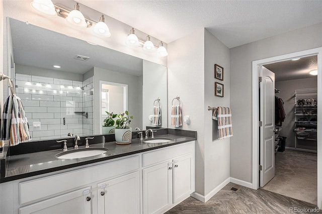 1473 Castle Creek Cir, Castle Rock, CO 80104 - bathroom featuring double vanity, a shower stall, a walk in closet, and a textured ceiling