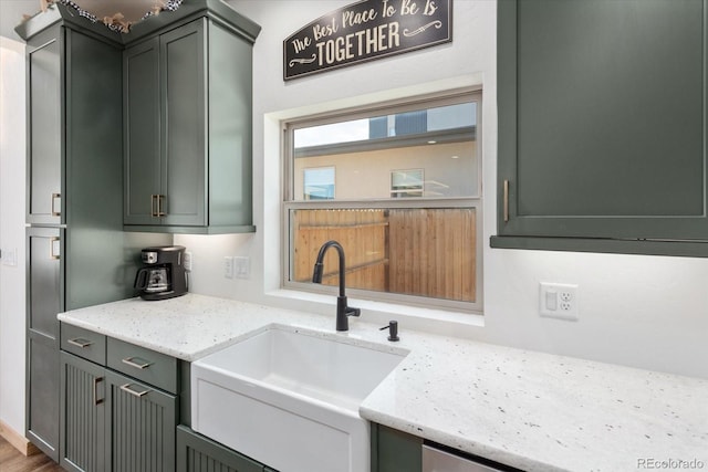 kitchen featuring wood-type flooring, light stone countertops, and sink