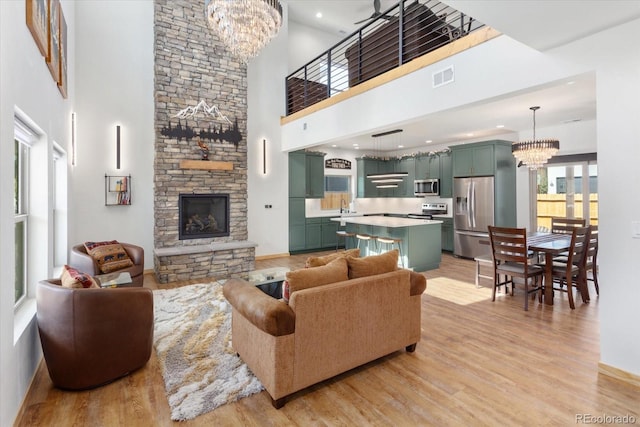 living room featuring a fireplace, a high ceiling, light hardwood / wood-style floors, and sink