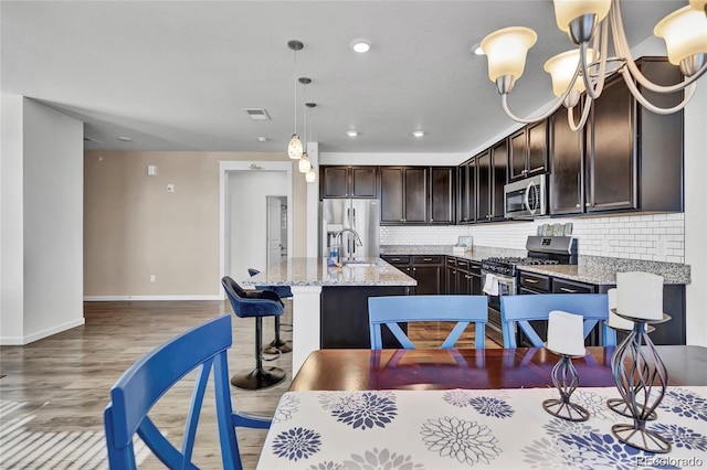 4569 Copeland Loop Unit 203, Highlands Ranch, CO 80126 - kitchen featuring stainless steel appliances, dark brown cabinets, backsplash, a kitchen island with sink, and recessed lighting