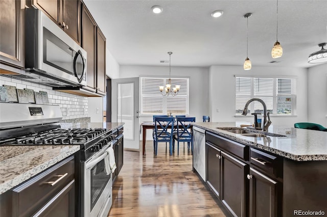 4569 Copeland Loop Unit 203, Highlands Ranch, CO 80126 - kitchen with stainless steel appliances, tasteful backsplash, a chandelier, dark brown cabinetry, and wood finished floors
