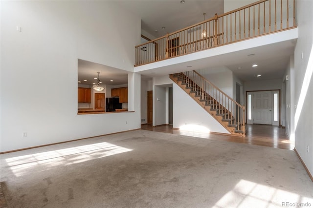 5571 S Sicily St, Aurora, CO 80015 - unfurnished living room featuring carpet, stairs, a high ceiling, and recessed lighting