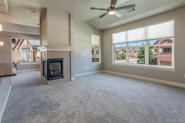 unfurnished living room with a tile fireplace, ceiling fan, light carpet, and vaulted ceiling