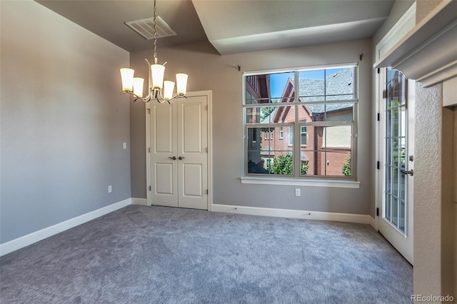 empty room with carpet and a notable chandelier