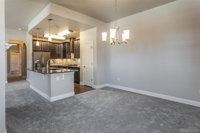 kitchen with stainless steel refrigerator with ice dispenser, dark brown cabinets, a kitchen island with sink, sink, and hanging light fixtures