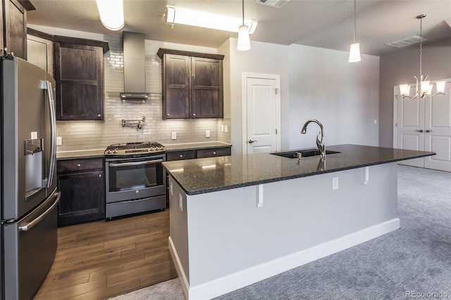 kitchen with stainless steel appliances, a center island with sink, wall chimney exhaust hood, and sink