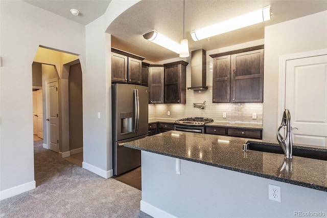 kitchen featuring wall chimney range hood, sink, dark stone countertops, carpet floors, and stainless steel appliances