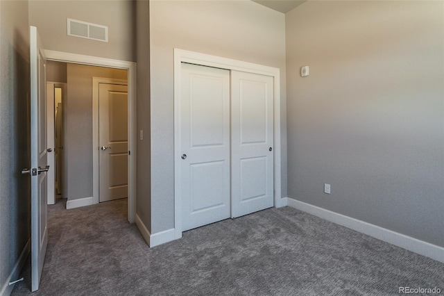 unfurnished bedroom featuring dark carpet and a closet