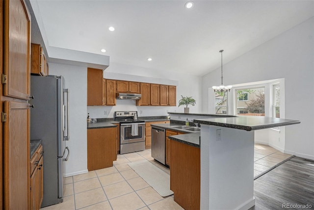 kitchen with stainless steel appliances, under cabinet range hood, a sink, dark countertops, and recessed lighting