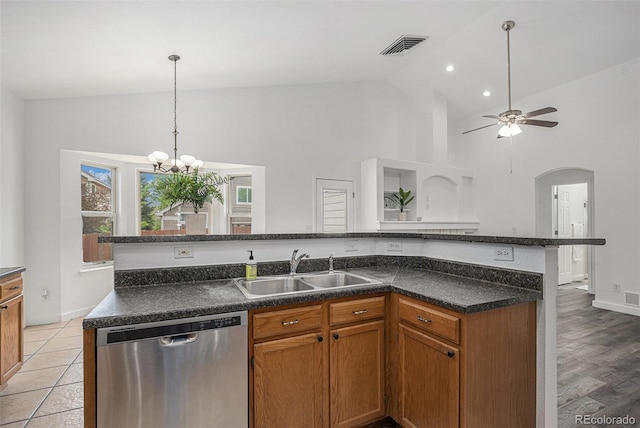 kitchen featuring stainless steel dishwasher, a sink, high vaulted ceiling, dark countertops, and brown cabinets