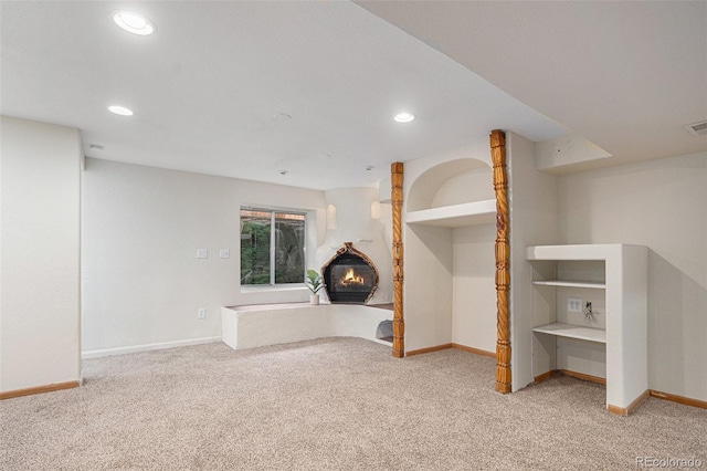 basement featuring light carpet, baseboards, recessed lighting, and a fireplace