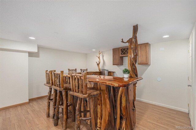 indoor bar with light wood-type flooring, baseboards, and recessed lighting