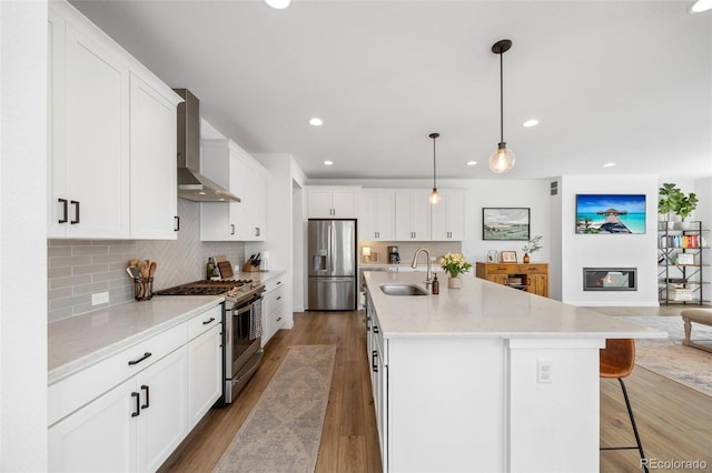 9016 Moondance Dr, Littleton, CO 80125 - kitchen with stainless steel appliances, wall chimney exhaust hood, recessed lighting, a breakfast bar, and backsplash