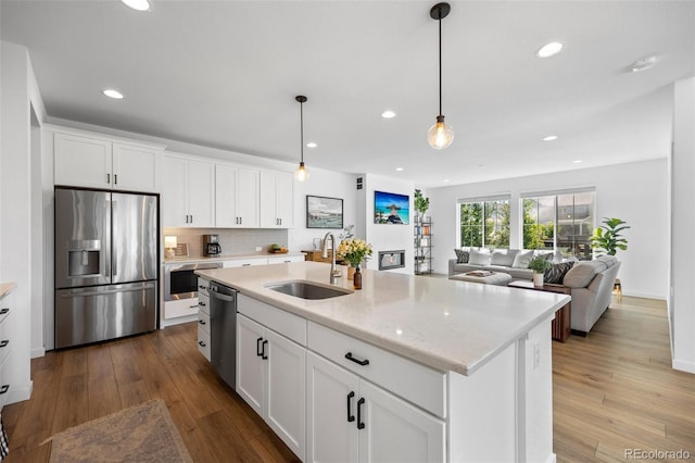 9016 Moondance Dr, Littleton, CO 80125 - kitchen featuring appliances with stainless steel finishes, hardwood / wood-style floors, recessed lighting, white cabinetry, and hanging light fixtures