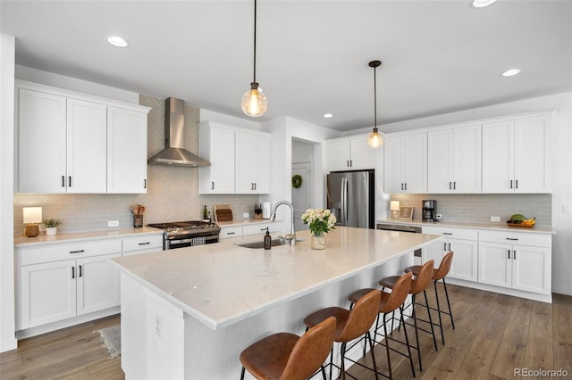 9016 Moondance Dr, Littleton, CO 80125 - kitchen with stainless steel appliances, wall chimney range hood, decorative backsplash, a breakfast bar area, and recessed lighting