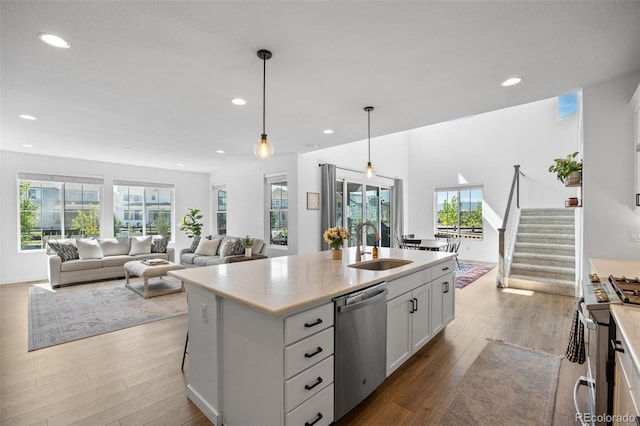 9016 Moondance Dr, Littleton, CO 80125 - kitchen with appliances with stainless steel finishes, white cabinets, light countertops, wood finished floors, and recessed lighting