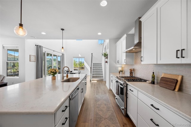 9016 Moondance Dr, Littleton, CO 80125 - kitchen with appliances with stainless steel finishes, wall chimney range hood, a kitchen island with sink, backsplash, and white cabinets