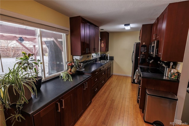 18908 E Napa Dr, Aurora, CO 80013 - kitchen featuring appliances with stainless steel finishes, a sink, dark countertops, light wood-type flooring, and plenty of natural light
