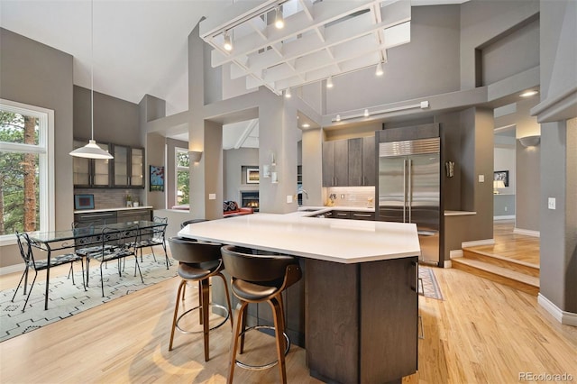 kitchen with a sink, decorative backsplash, light countertops, light wood-style floors, and built in fridge