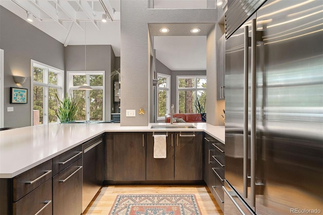 kitchen featuring a sink, appliances with stainless steel finishes, light countertops, and dark brown cabinets