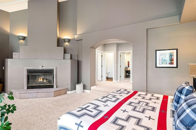 bedroom with a fireplace, arched walkways, carpet floors, and baseboards