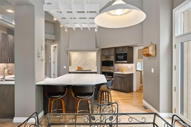 kitchen featuring tasteful backsplash, dark brown cabinetry, black microwave, and a sink