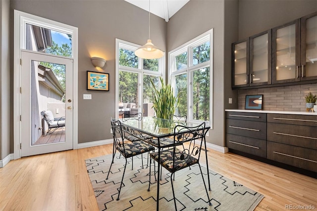 dining space featuring a high ceiling, light wood-type flooring, and baseboards