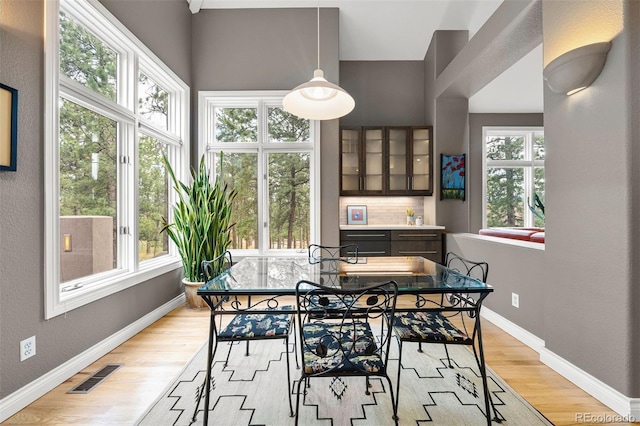 dining room with light wood-style flooring, plenty of natural light, baseboards, and visible vents