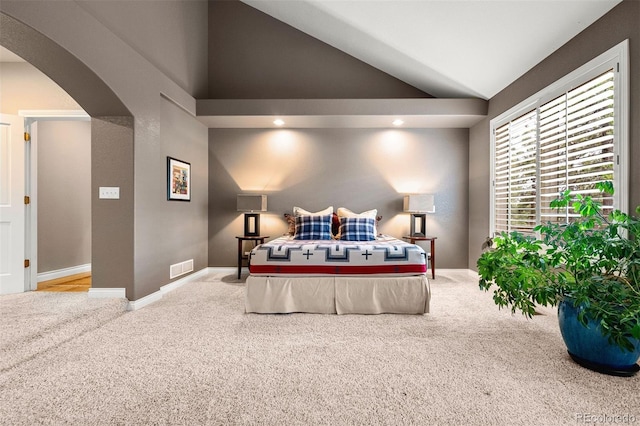 carpeted bedroom with arched walkways, visible vents, baseboards, and lofted ceiling