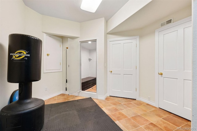 exercise room featuring light tile patterned floors, baseboards, and visible vents