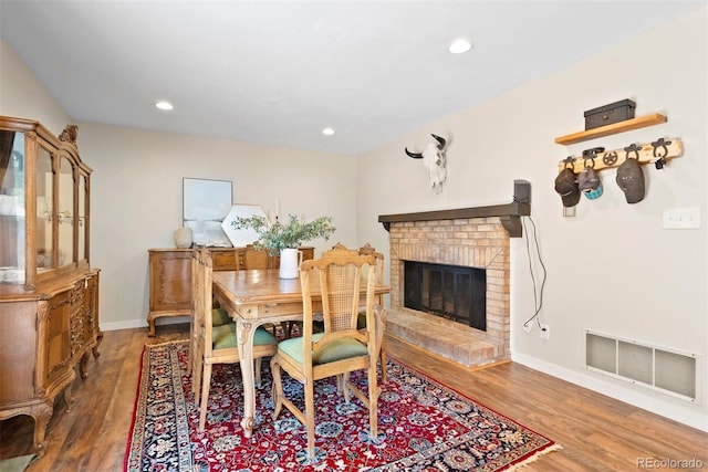 dining room with dark wood-style floors, visible vents, a fireplace, and baseboards