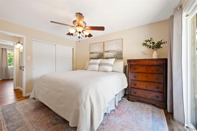 bedroom with dark wood-style flooring, a closet, a ceiling fan, and baseboards