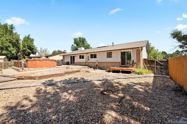 back of property featuring a patio, a jacuzzi, a fenced backyard, a wooden deck, and brick siding