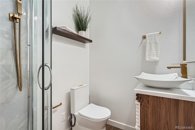 full bathroom with toilet, a shower stall, baseboards, and vanity