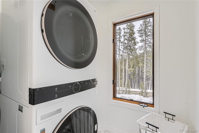 laundry area with laundry area, stacked washer / dryer, and a healthy amount of sunlight