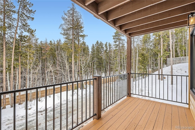 snow covered deck with a wooded view