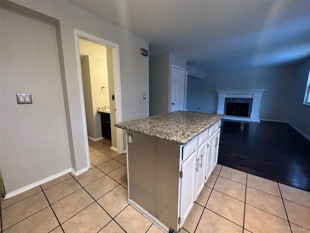 kitchen featuring light tile flooring, stone countertops, and white cabinetry