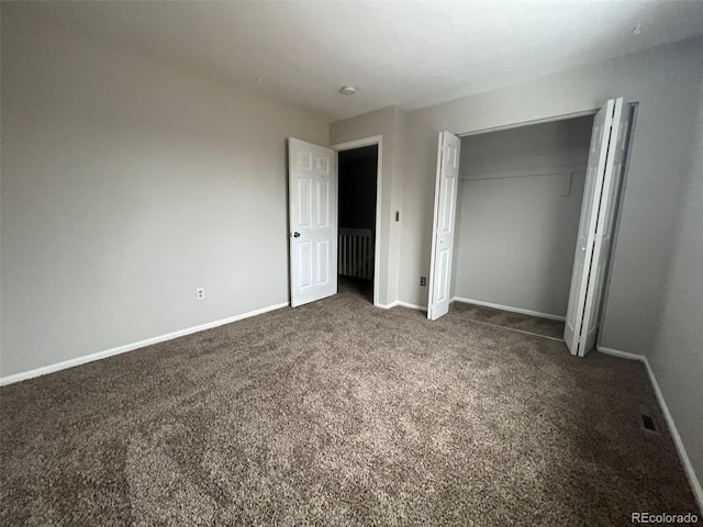 unfurnished bedroom featuring a closet and dark carpet