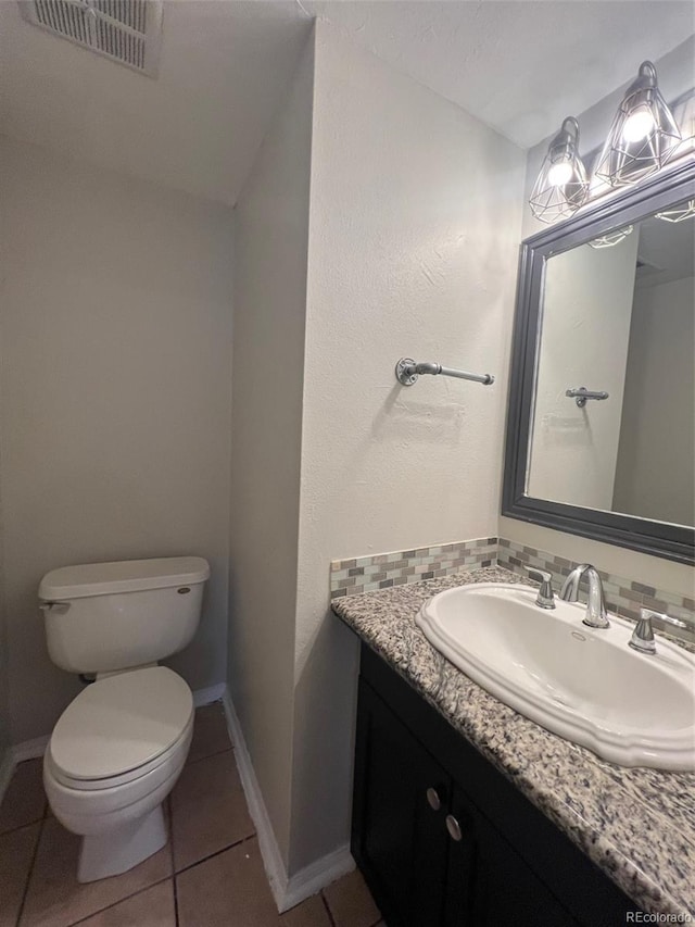 bathroom with toilet, vanity with extensive cabinet space, and tile flooring