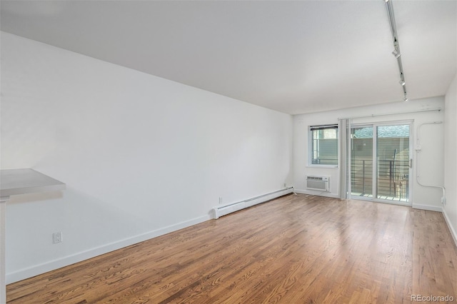 1245 Columbine St Unit 306, Denver, CO 80206 - empty room featuring baseboard heating, rail lighting, a wall mounted AC, and wood finished floors