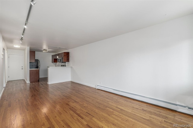 1245 Columbine St Unit 306, Denver, CO 80206 - unfurnished living room featuring a baseboard heating unit, wood finished floors, and track lighting