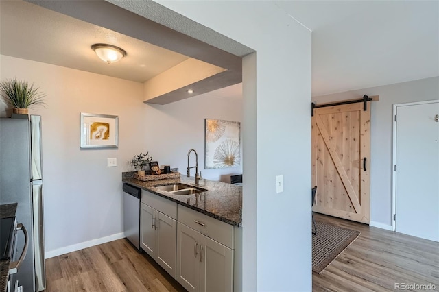 499 Wright St Unit 308, Lakewood, CO 80228 - kitchen with dark stone countertops, a barn door, light wood-style floors, appliances with stainless steel finishes, and a sink