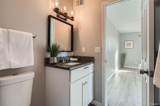 499 Wright St Unit 308, Lakewood, CO 80228 - half bathroom featuring vanity, visible vents, toilet, wood finished floors, and baseboards