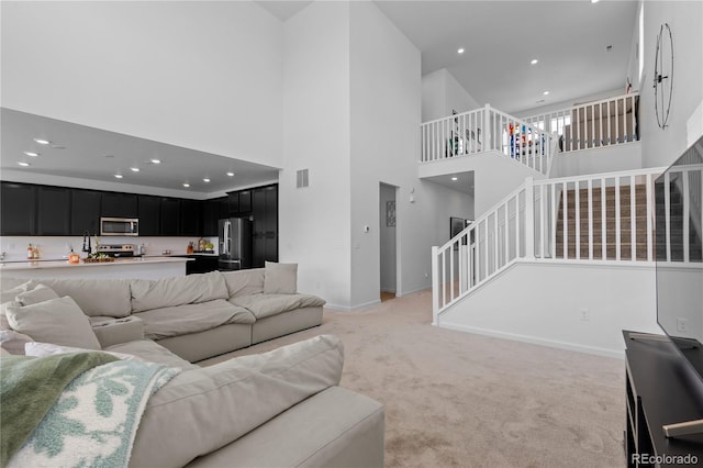 8550 Cheraw St, Littleton, CO 80125 - living room featuring a high ceiling, stairway, light colored carpet, and recessed lighting
